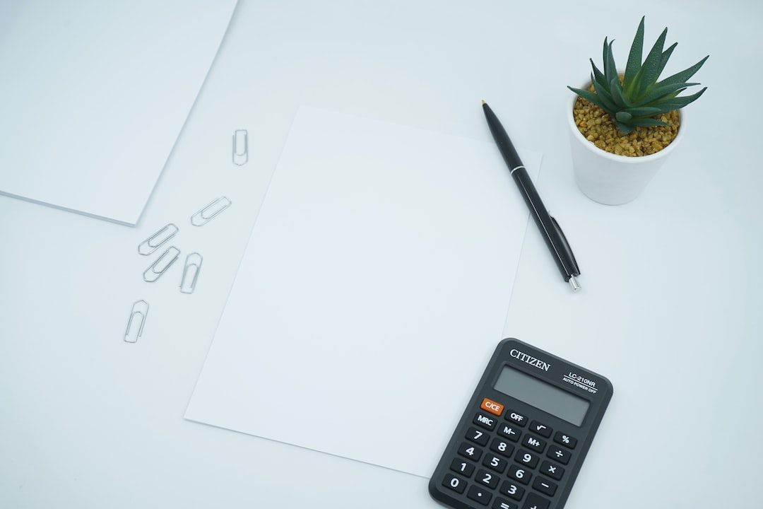 black calculator beside black pen on white printer paper